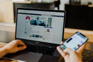 A person is using a laptop with a facebook page on it.