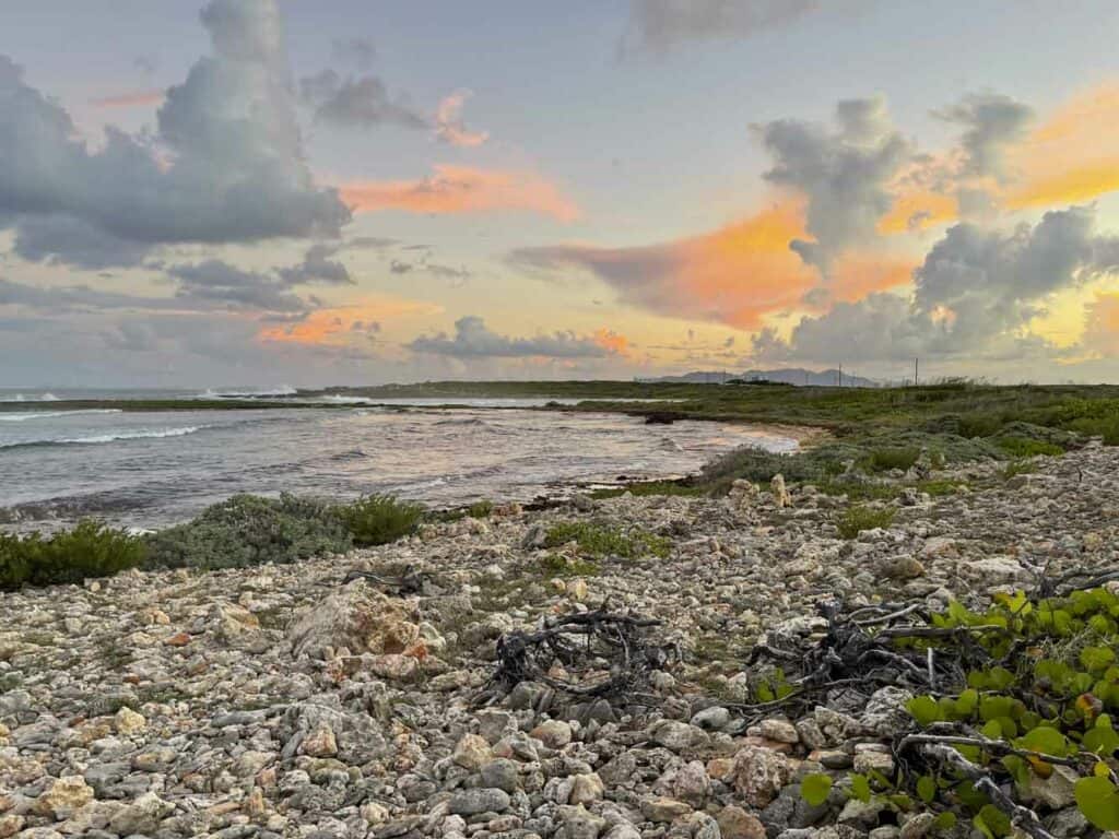 A sunset over a beach with rocks and sand.