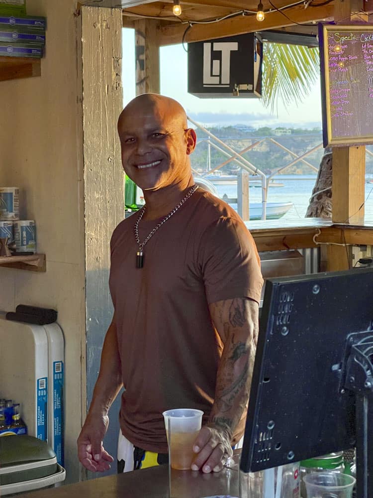 A man standing in front of a bar with a drink in his hand.