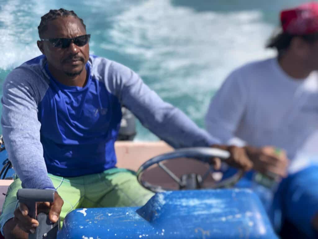 Two men riding on a blue boat in the ocean.