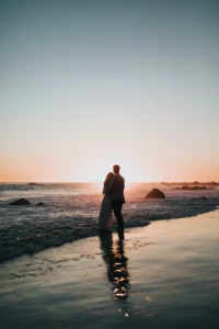 A beachside bride and groom in Anguilla, surrounded by the romantic glow of sunset, enjoying their honeymoon.