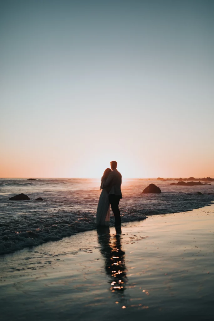 A beachside bride and groom in Anguilla, surrounded by the romantic glow of sunset, enjoying their honeymoon.